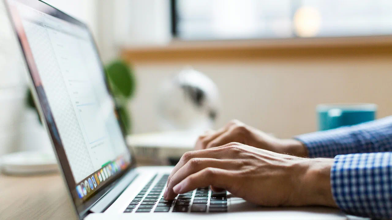 A pair of hands typing on a silver laptop keyboard